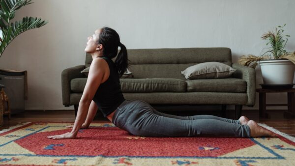 Woman doing yoga cobra pose in a tranquil indoor setting on a vibrant carpet.